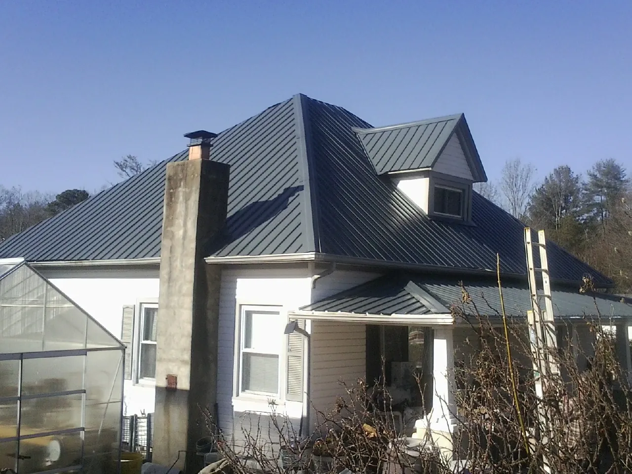 Dark blue standing seam metal roof on a white farmhouse with dormer — Slate & Tile Roof Repair by Roofing Brothers in Nicktown