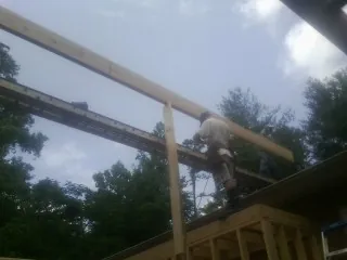 Carpenter setting a ridge beam over a new addition frame — Ice Dam Removal by Roofing Brothers in Nicktown