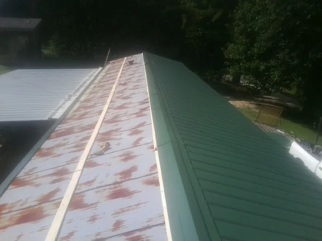 Old rusted panels beside newly installed green metal roofing — Wind Damage Roof Repair by Roofing Brothers in Nicktown