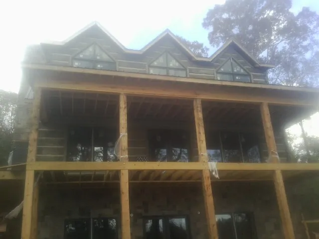 Dormers and porch framing on a large log home under construction — Roof Coating work by our crew in Nicktown