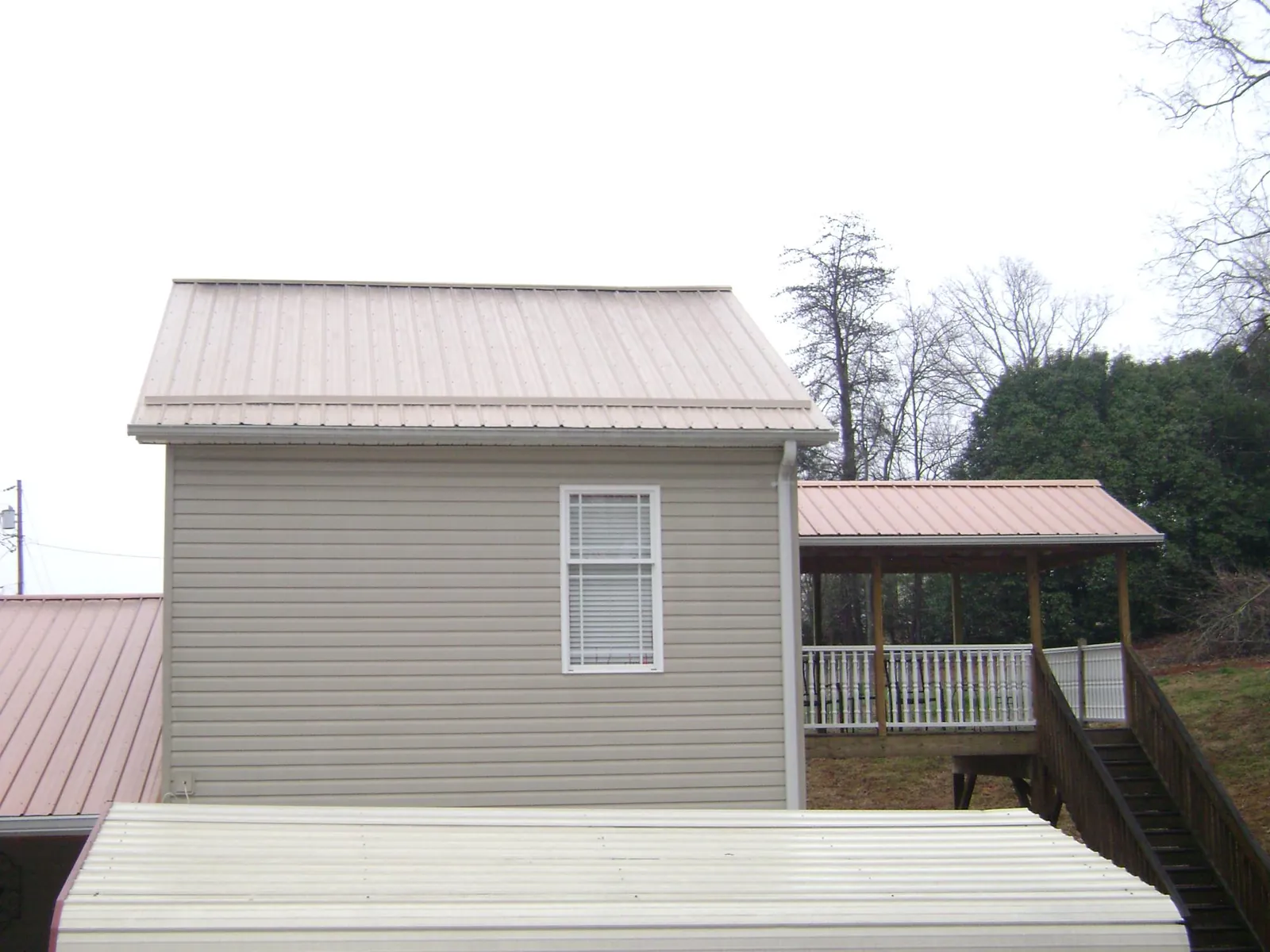 Tan metal roofs on a two story addition and attached porch, from a Roof Replacement job in Nicktown