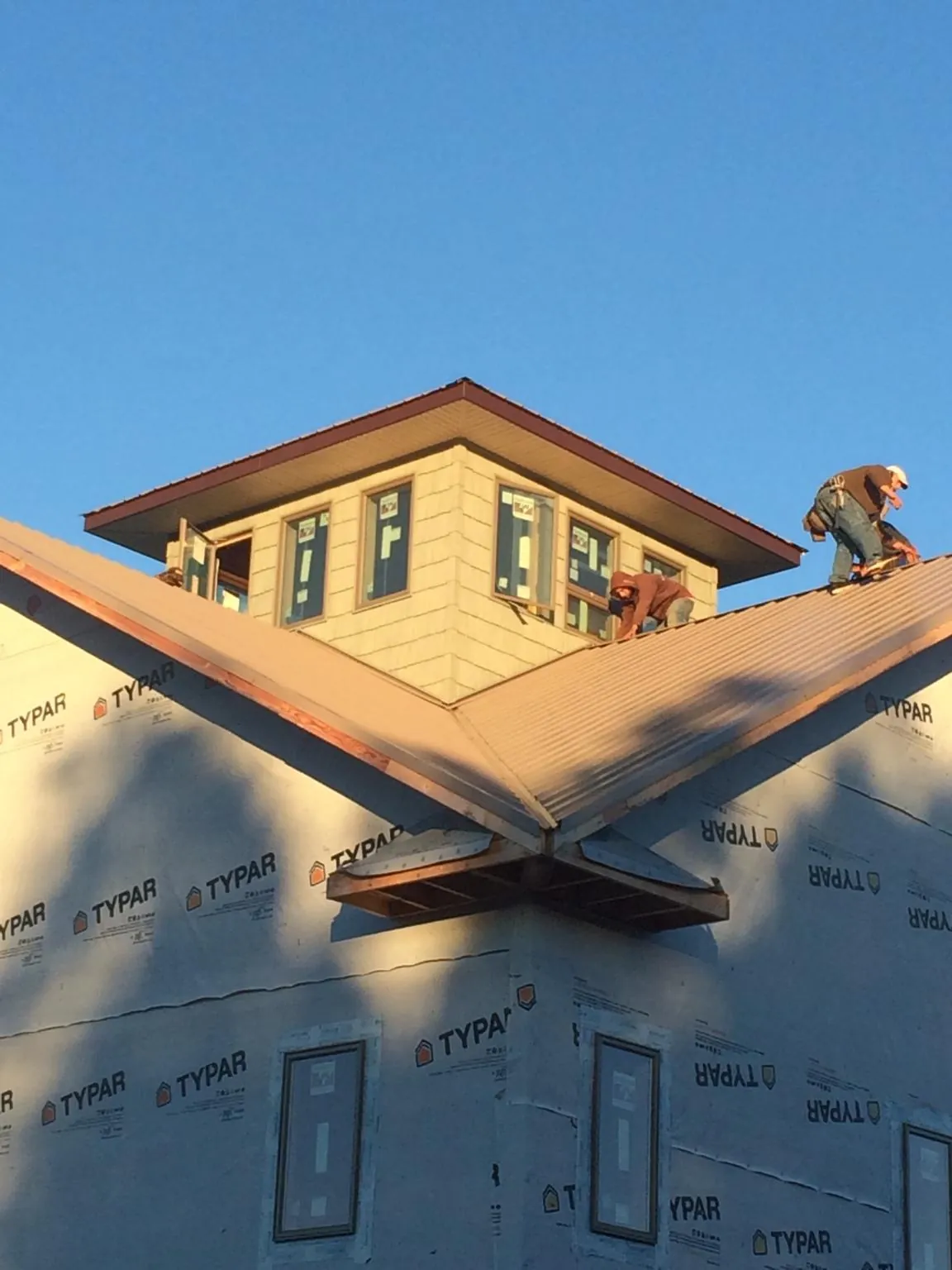 Roofers working around a rooftop cupola on a new metal roof at sunset — Roof Waterproofing in Nicktown by Roofing Brothers